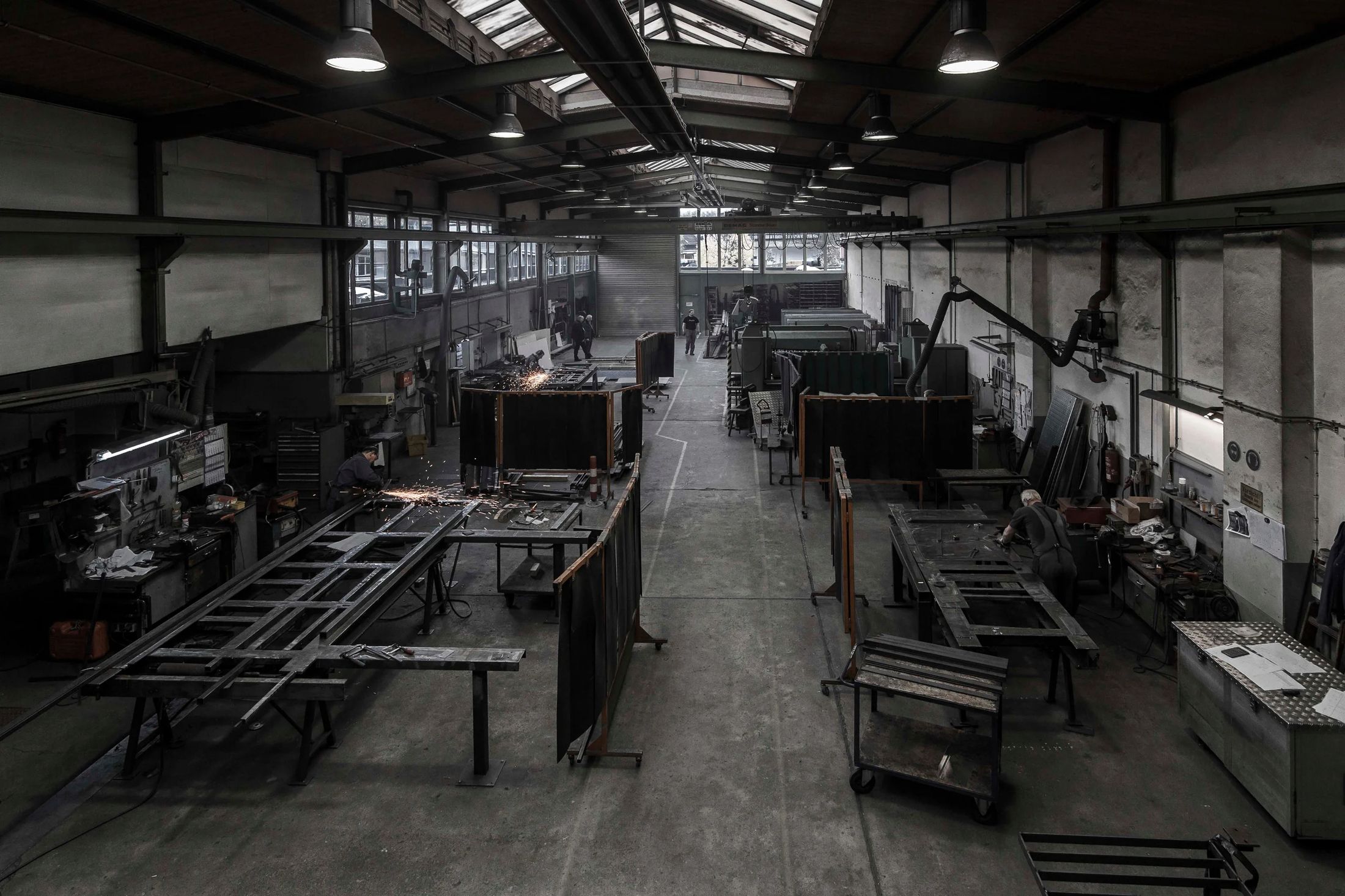 Moderne Metallbauwerkstatt mit Arbeitstischen, Schweißequipment und Fachpersonal bei der Arbeit